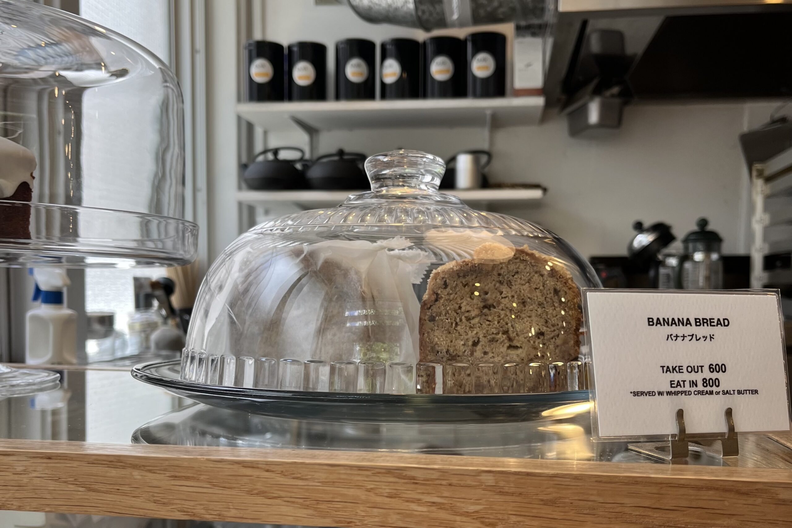 Banana bread under a glass cloche on the counter at Buik